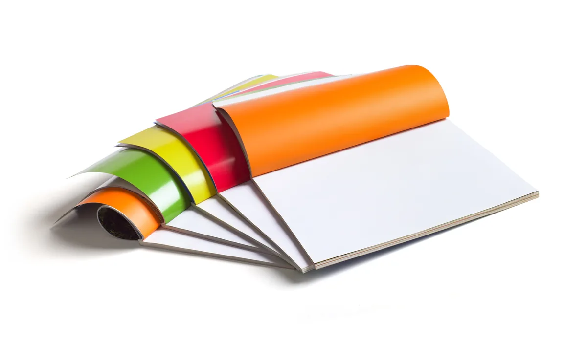 Brochures agrafées en couleur posées à plat sur un fond blanc