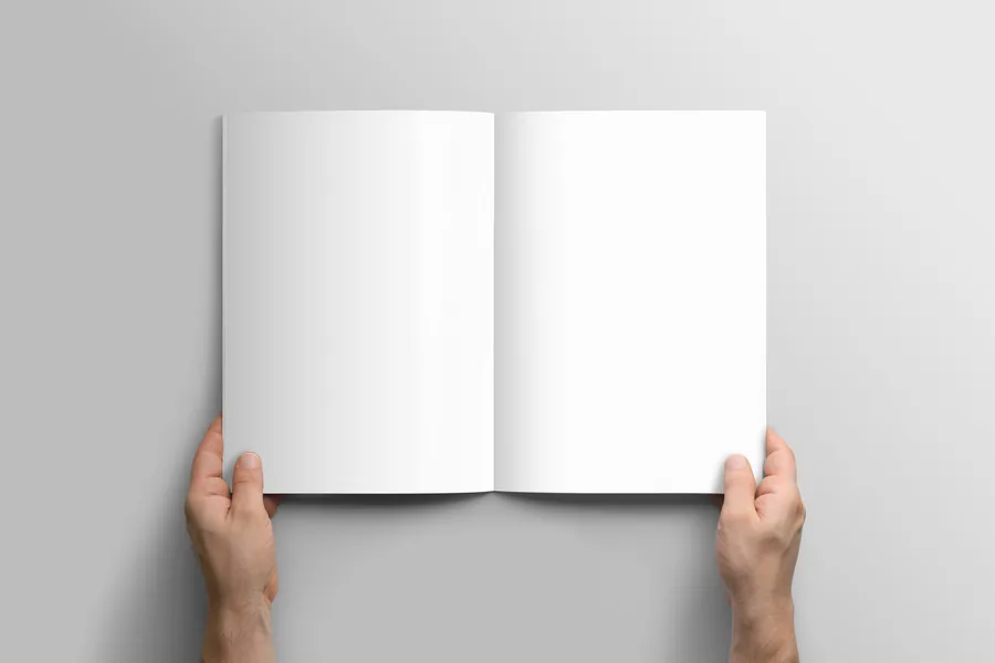 Mains tenant une brochure A4 ouverte sur une double page illustrée