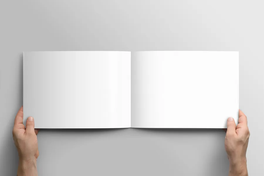 Mains tenant un catalogue au format A4 paysage ouvert sur une double page