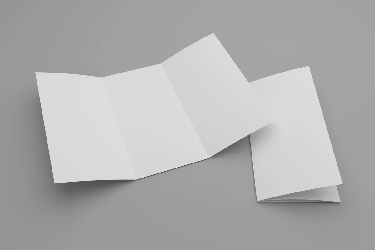 Dépliant 3 volets blanc ouvert à plat avec ses deux lignes de pli, posé à côté d’un exemplaire fermé