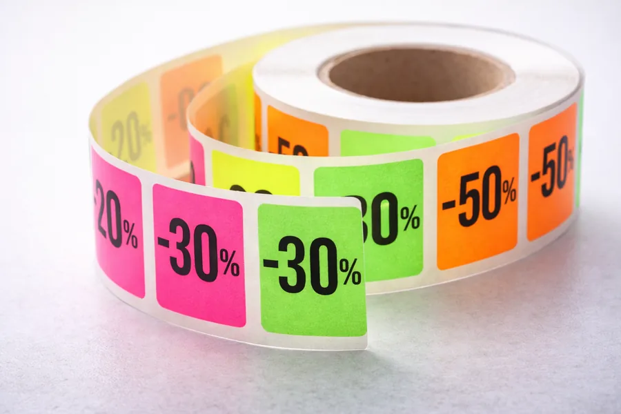 Rouleau d’étiquettes carrées fluorescentes roses, vertes et orange portant les remises -20 %, -30 % et -50 %