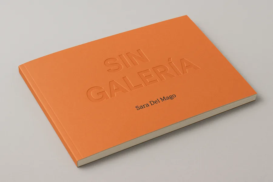 Livre broché à couverture souple orange mate, dos carré collé fin, posé à plat